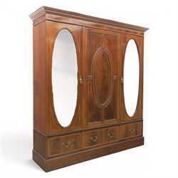 Edwardian inlaid mahogany triple wardrobe, featuring two oval mirror doors with bevelled p...