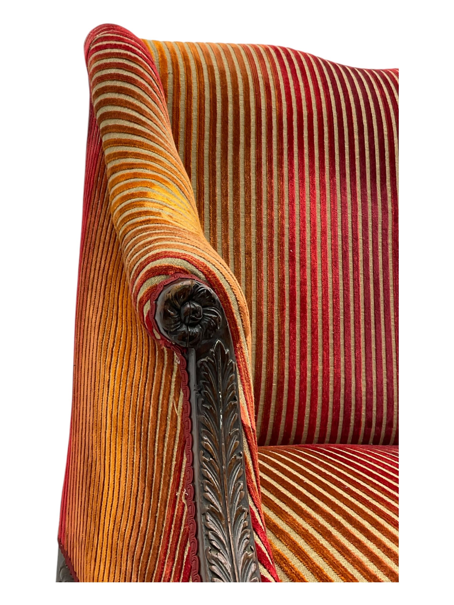 Mid-19th century mahogany two-seat sofa, upholstered in striped velvet fabric, the shaped backrest leading to outward-curved arms, carved apron with scrolling foliate details, raised on cabriole supports terminating in claw and ball feet