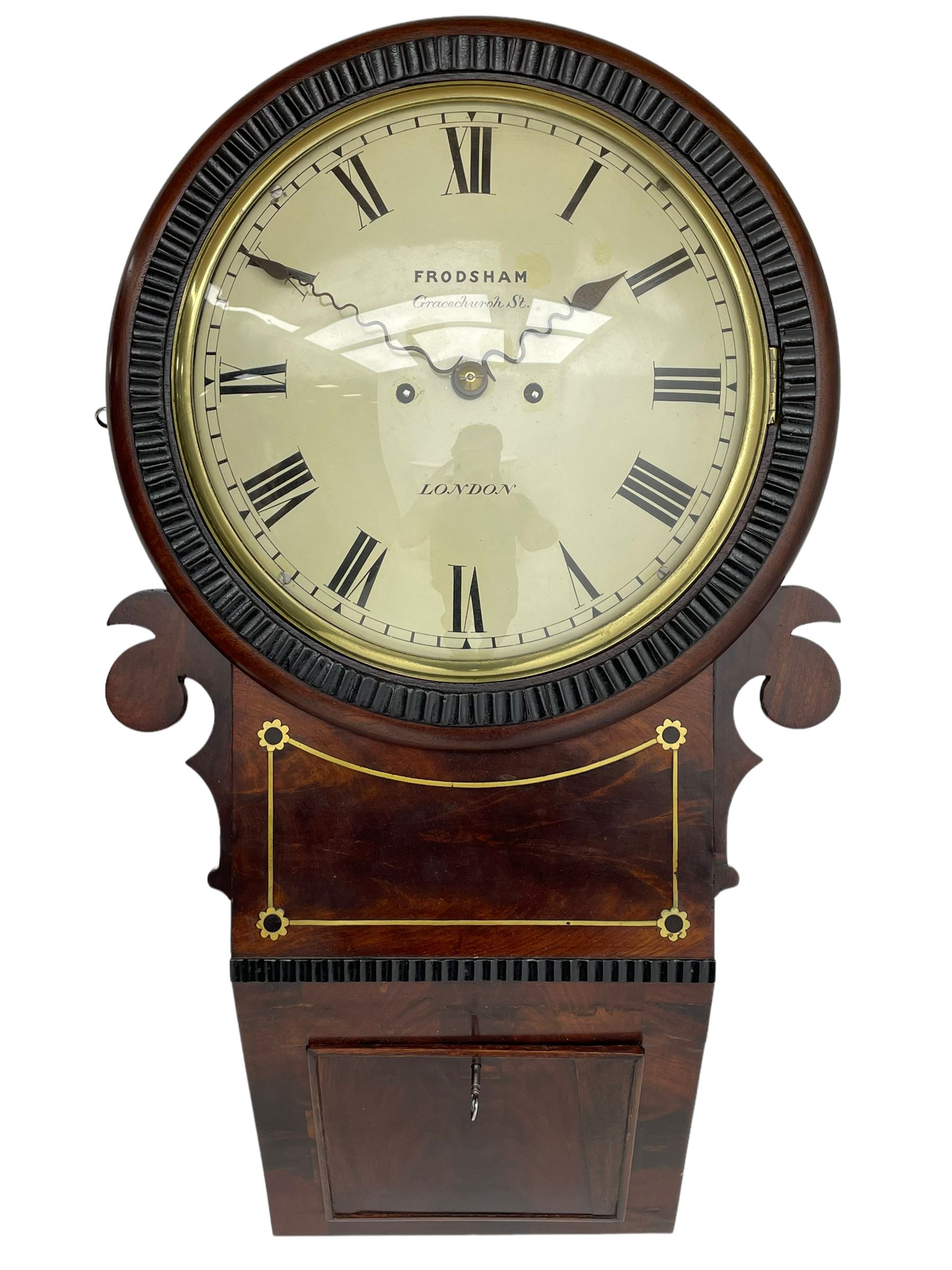 Frodsham of London - 8-day chain driven twin fusee wall clock in a mahogany case c1870, veneered case inlaid with brass stringing and motifs, shaped earpieces and chisel shaped base with pendulum adjustment door, 10” painted steel dial with Roman numerals, minute track and blued serpentine steel hands, dial inscribed Frodsham, Gracechurch Street, London, chain fusee, five-pillar, rack striking movement striking the hours on a cast bell. With pendulum.
H65 W34 D18
George Edward Frodsham, son of John Frodsham is recorded as working in Gracechurch Street, London 1869-79. Succeeded to Frodsham & Baker
