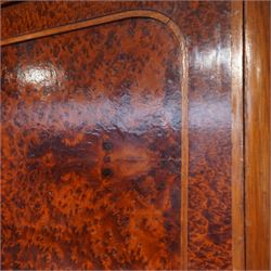 Early 20th century French burr maple breakfront armoire, enclosed by three panelled doors with bookmatched veneer and stringing, outer doors inlaid with gilt urn medallions, fitted interior with hanging spaces flanking a shelved compartment, raised on short tapered legs