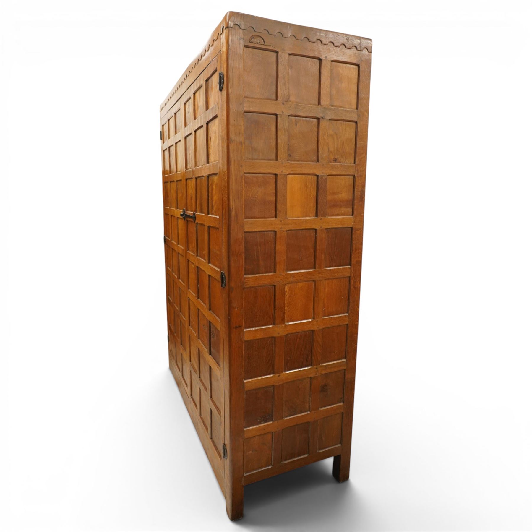 Mouseman - early-to-mid-20th century figured panelled and adzed double wardrobe of large proportions, the arcade carved cresting rail over two doors with adzed and figured oak panels, with wrought metal hinges and latch, relief carved mouse signature, the interior fitted with hanging rail, by the workshop of Robert Thompson, Kilburn