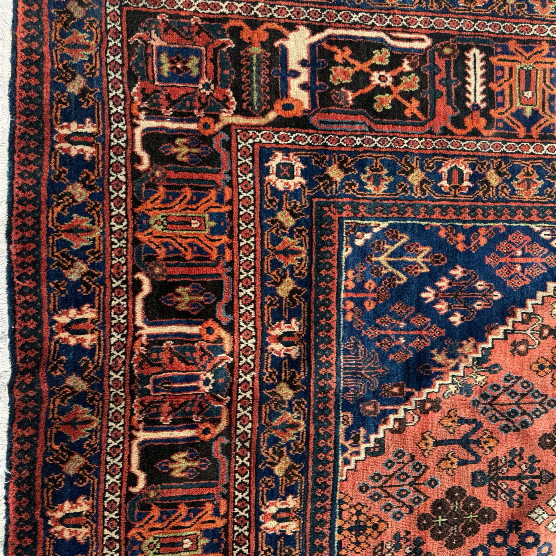 Joshgan Persian wool rug, with diamond-framed medallion, on a deep red field filled with geometric-shaped floral motifs and indigo-filled spandrels 