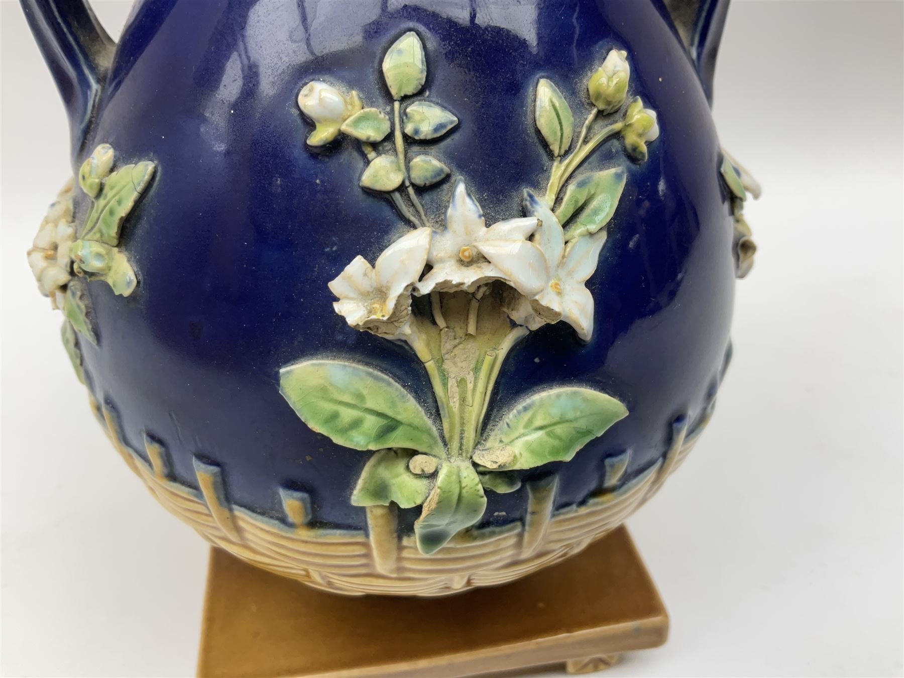 Minton majolica vase, the squat body with twin handles, with part osier moulding and applied Spring flowers against a cobalt blue ground, upon integral square base, impressed beneath Minton 1316, H16.5cm