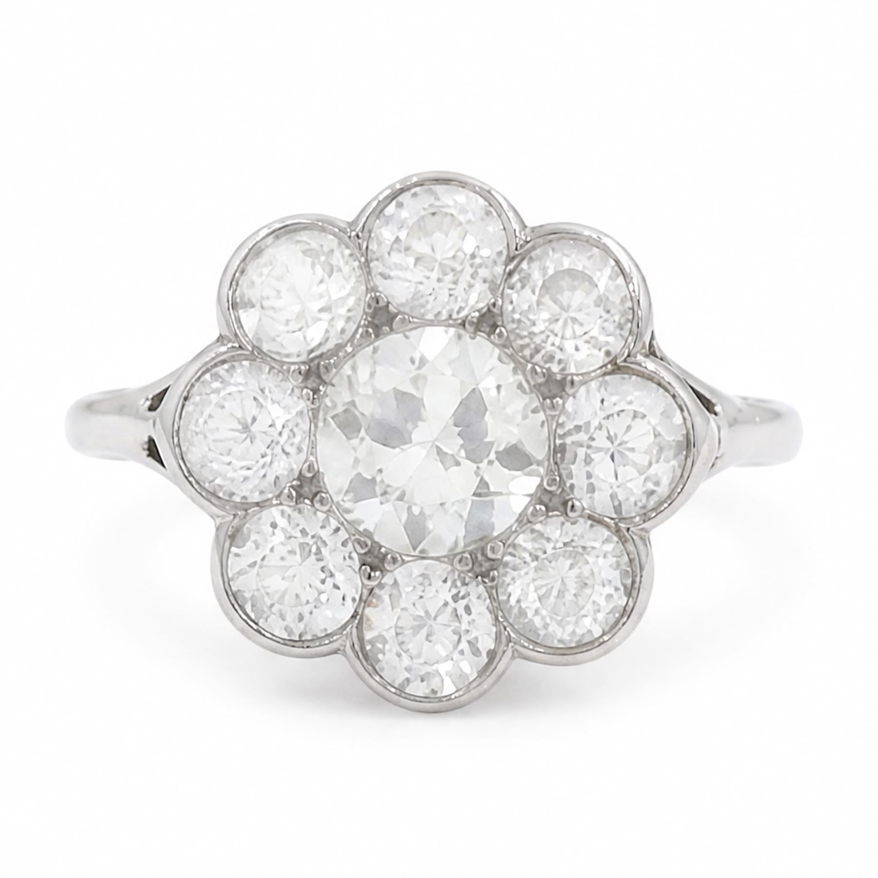 Early 20th century platinum diamond daisy flower head cluster ring, principal round cut diamond of approx 0.65 carat, surrounded by eight milgrain set old cut diamonds, within a pierced scroll design gallery, total diamond weight approx 2.15 carat