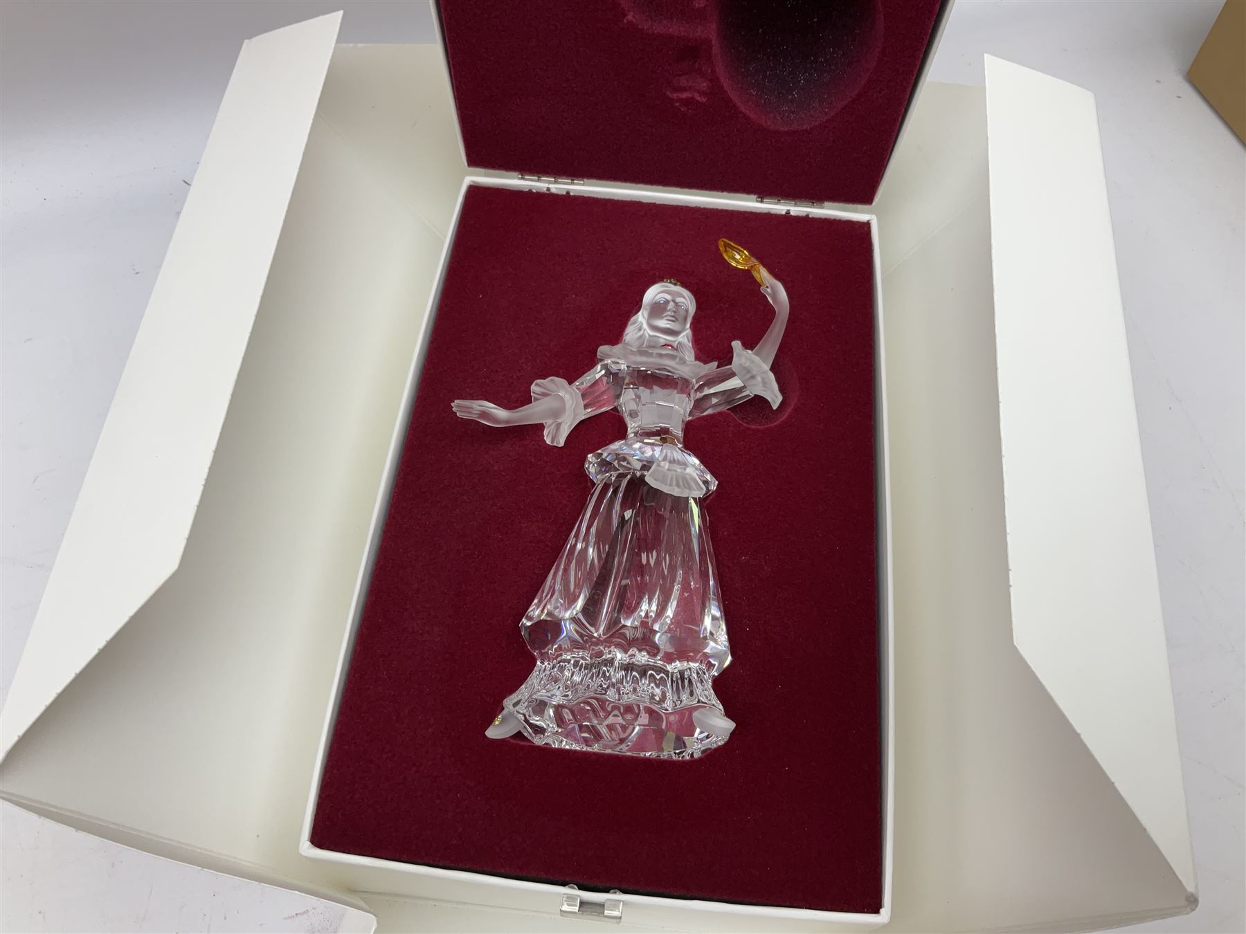 Swarovski Crystal Masquerade trilogy; 1999 Masquerade Pierrot, 2000 Columbine, 2001 Harlequin all with accompanying plaque, stand and original box, together with a glass display case with mirrored back and sides 