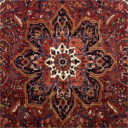 North West Persian Ahar hand-knotted carpet, madder red ground, with a large central shaped floral medallion with pendants, surrounded by angular scrolling foliate motifs incorporating rosettes, palmettes and stylised flowerheads, enclosed by ivory spandrels and a dark navy border with repeating floral motifs and meandering vines, flanked by narrow floral guard stripes, with cotton fringes