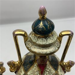 Pair of Vienna style twin handled urns and covers, decorated with figural scene on green, red and white ground with gilt highlights, stamped with beehive mark beneath, H25cm