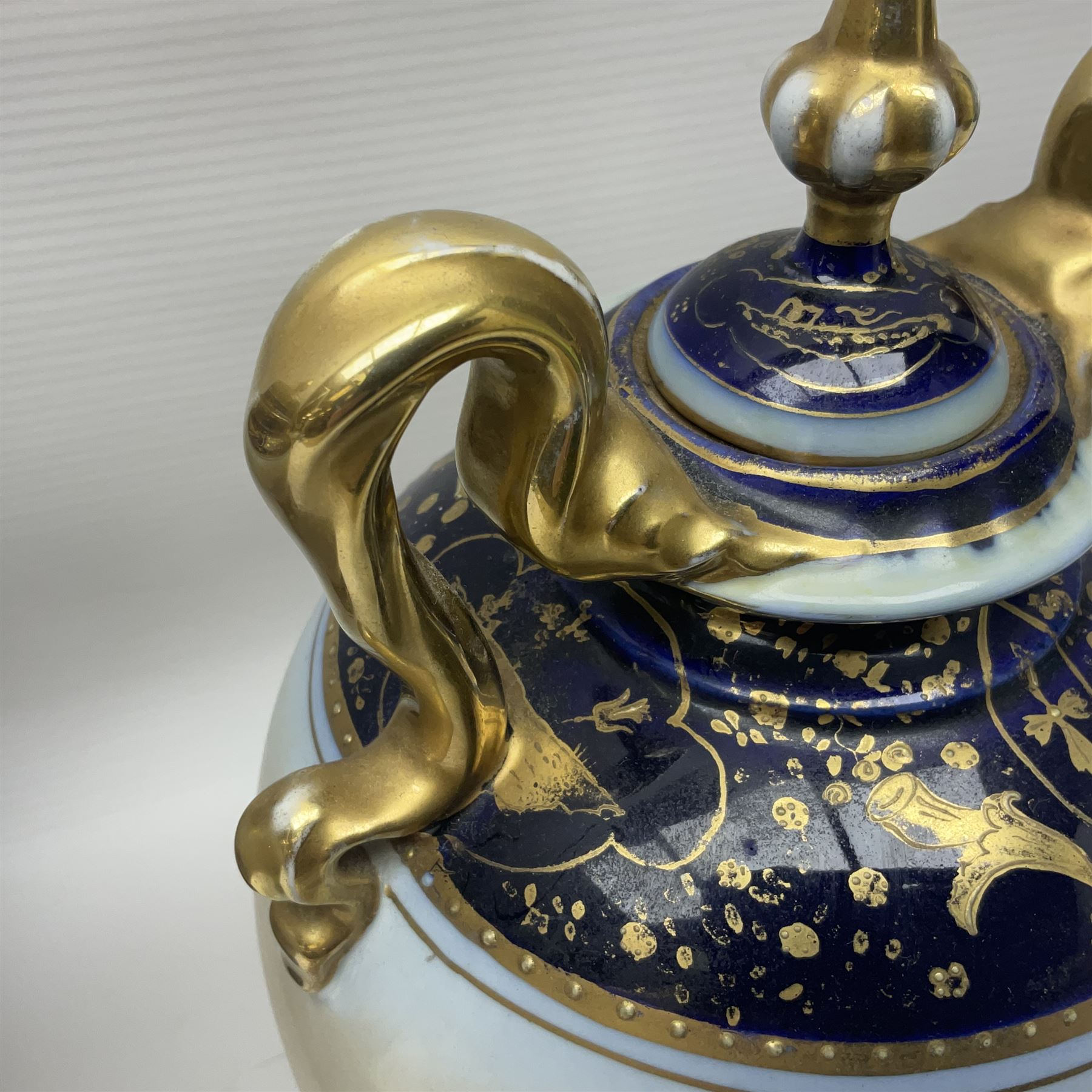 19th century Vienna style porcelain 'Musik' garniture, the central vase of baluster form with domed cover flanked by two smaller vases with twin curved gilt handles to short neck, each decorated with classical figural vignettes between blue borders heightened with gilt, H33.5cm