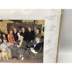 Photograph of the cast of Heartbeat posing in costume in the Aidensfield Arms and signed by twelve cast members including John Duttine, Tricia Penrose, Clare Wille, Derek Fowlds, Gwen Taylor, Lisa Kay, Peter Benson etc; unframed