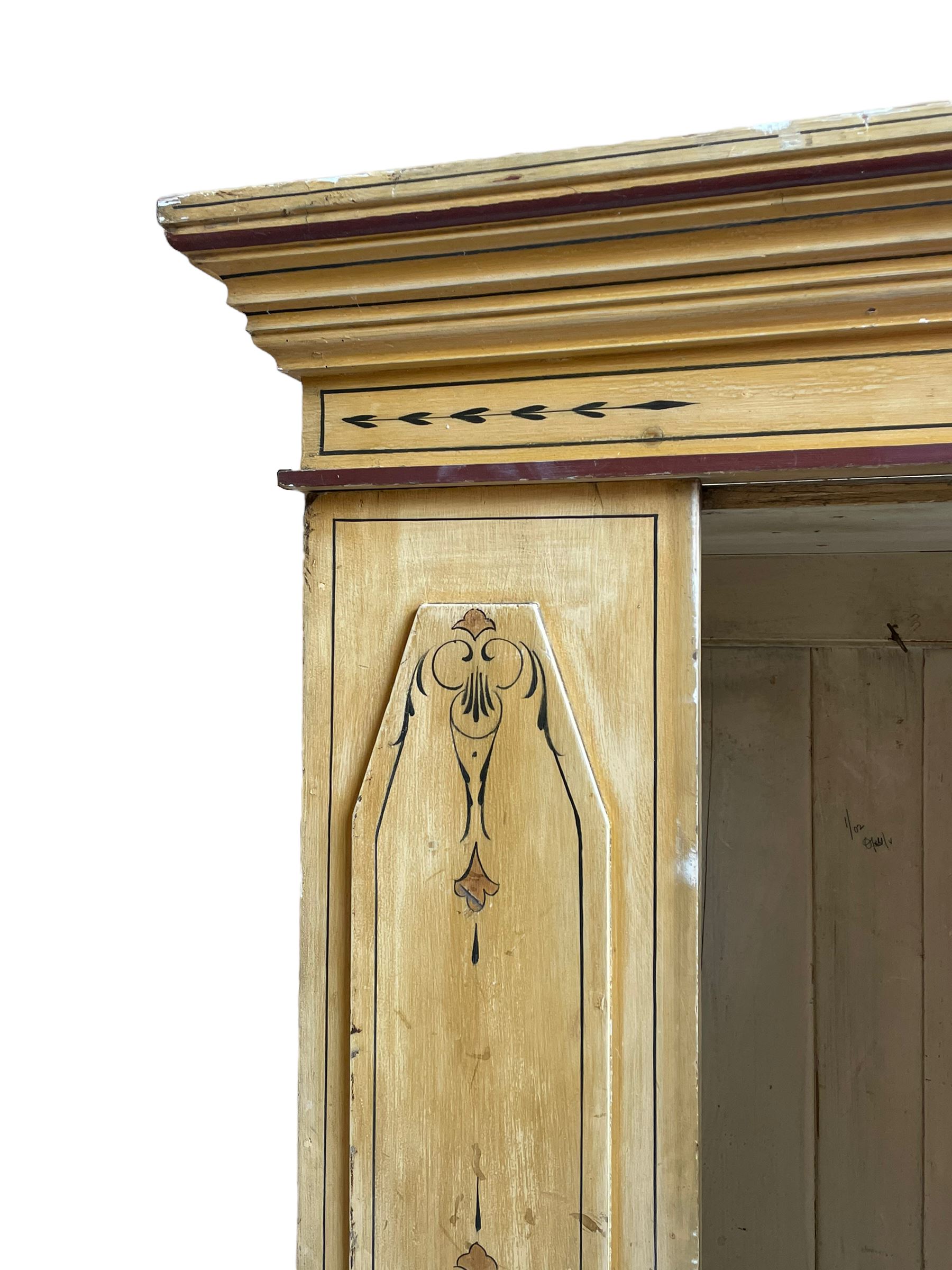 19th century painted pine wardrobe, the projecting cornice over mirror glazed door, with painted decoration depicting scrolling foliate and urns, drawer to base on skirt