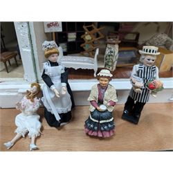 Two modern three storey dolls houses, each painted green with decorated interiors, both upon a single white wooden base, together with a large collection of dolls house furniture, accessories and figures 