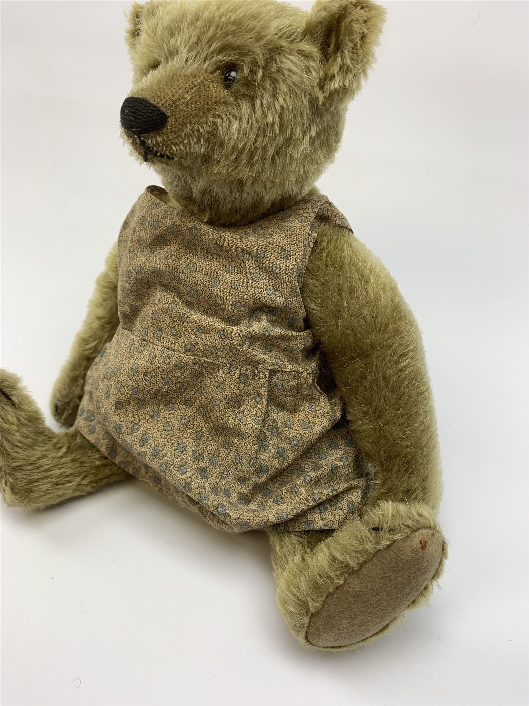 Early 20th century German Steiff teddy bear c1910 with wood wool filled humped back mohair body, swivel jointed head with black boot button eyes and horizontally stitched black nose and mouth, FF metal button to left ear, jointed elongated limbs with felt paw pads and black stitched claws H13