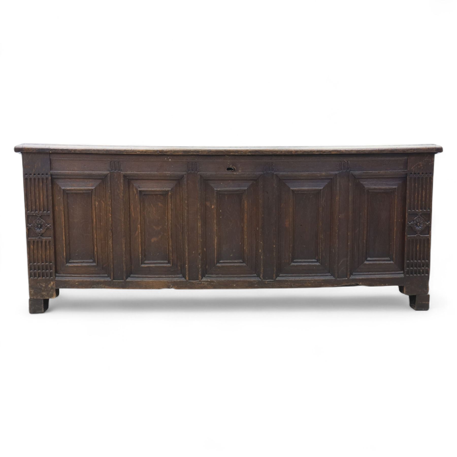 18th century oak five panel chest, with planked top with chamfered edges, hinged top enclosing two candle boxes, five fielded panels flanked by foliate carvings, raised on stile supports