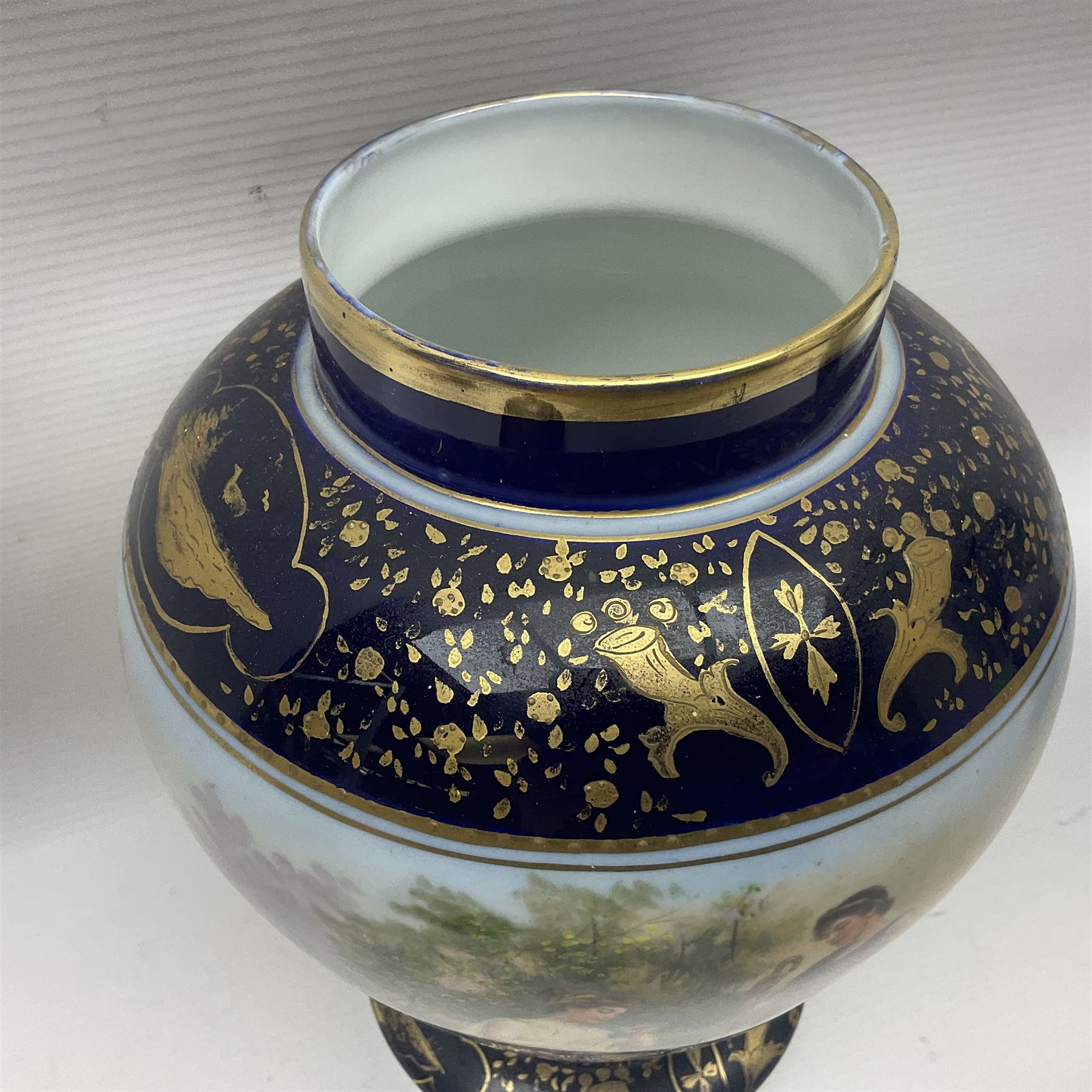 19th century Vienna style porcelain 'Musik' garniture, the central vase of baluster form with domed cover flanked by two smaller vases with twin curved gilt handles to short neck, each decorated with classical figural vignettes between blue borders heightened with gilt, H33.5cm
