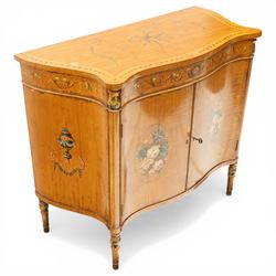 Sheraton Revival satinwood serpentine-front cabinet, the shaped cross-banded top with ebony stringing and painted scrolls of acanthi and ribbon work with a bell-flower border, the banded frieze painted with repeating acanthus scrolls, the matched veneer doors painted with oval panels of floral bouquets, raised on turned and tapering supports