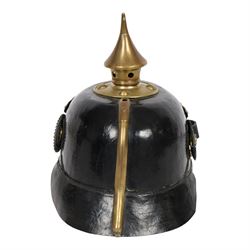 WWI Prussian guard regiment Pickelhaube, the black leather skull with brass ball finial, brass eagle helmet plate and leather chin strap, one side with a black  and white cockade, the other black, white and red, 