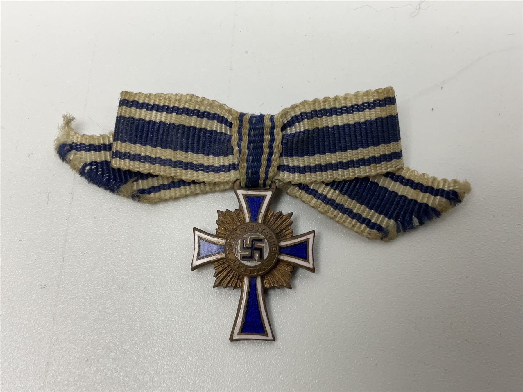 Four German awards - pre-WW2 two-position button hole ribbon for 1914 Iron Cross; WW1 wound badge open back cut-out version with silvered finish; miniature version Mother's Cross with ribbon bow; and The Eastern Medal, officially the Winter Battle in the East 1941–42 Medal (4)