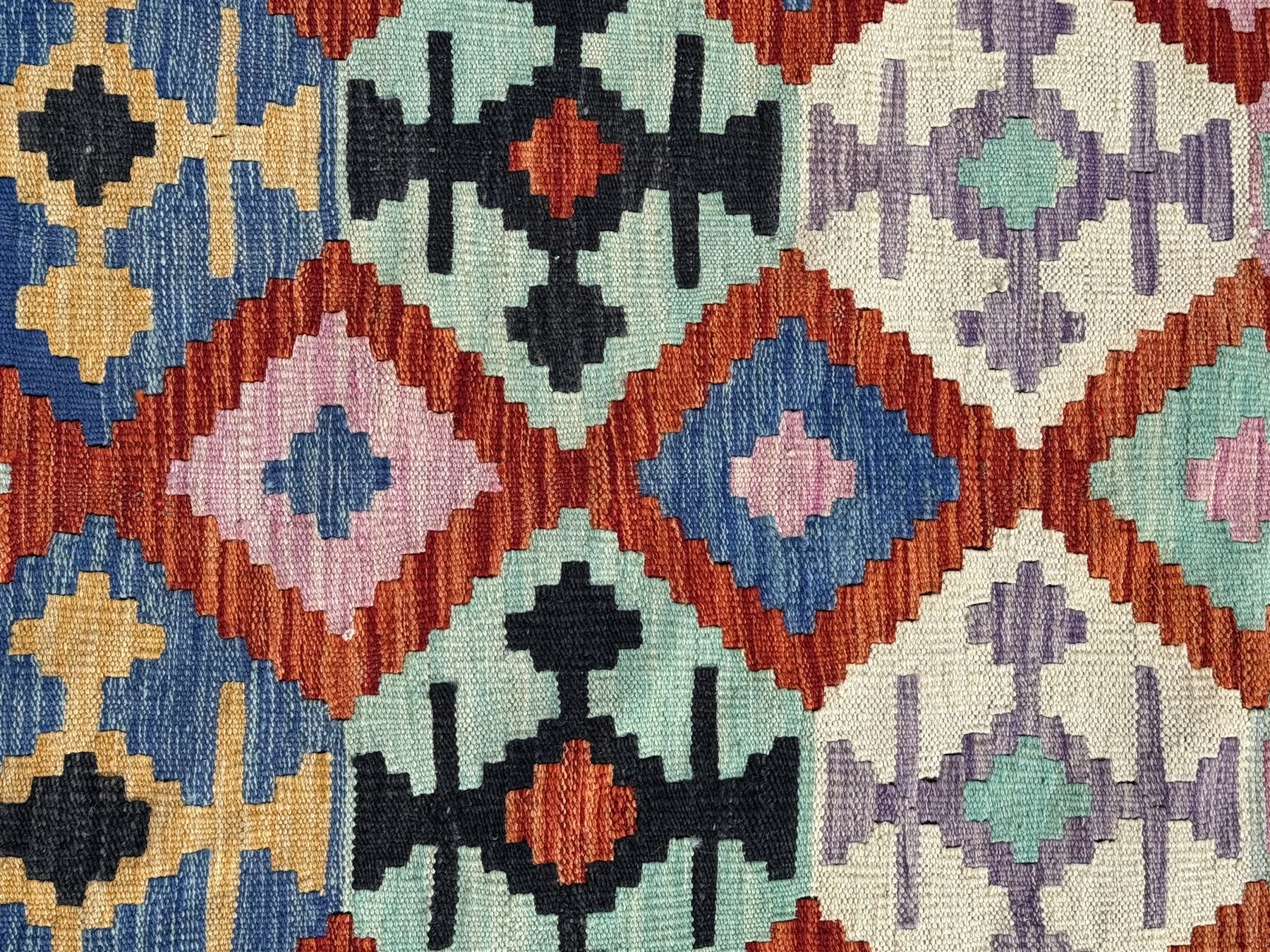Kilim pastel ground rug, the field decorated with repeating multicoloured geometric diamond motifs, enclosed within matching geometric borders