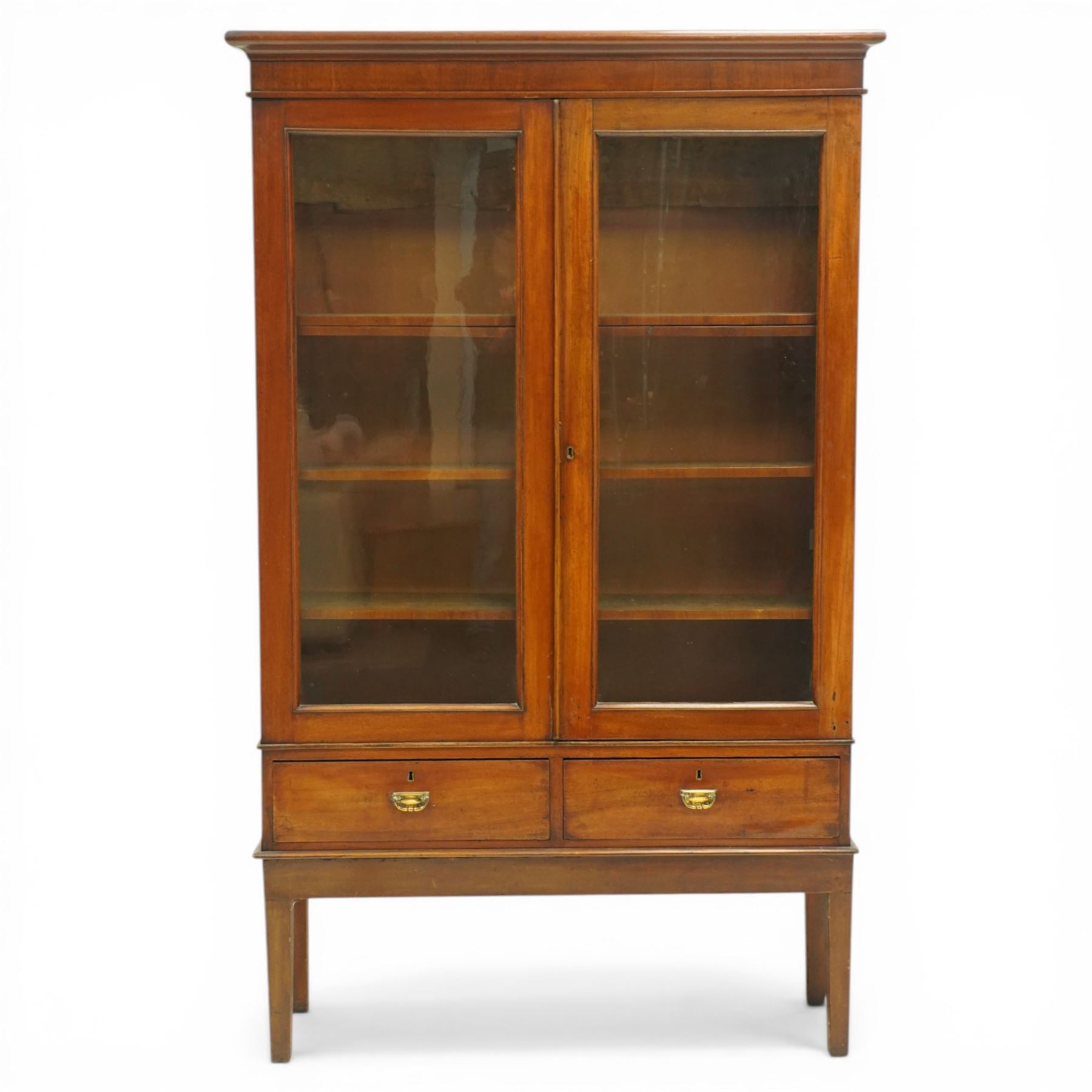 19th century mahogany enclosed bookcase on stand, projecting cornice and banded frieze over two glazed doors enclosing four adjustable shelves, fitted with two drawers to base, on square tapering supports