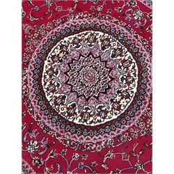 Persian red ground rug, circular central ivory medallion, the curved rectangular field decorated with interlacing branch and stylised plant motifs, the border with repeating floral scroll design