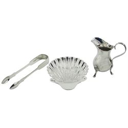 Early 20th century silver cream jug, the plain body of bellied form with curved strap handle, upon three hoof feet, hallmarked Josef Zweig, Birmingham 1911, together with a late Victorian silver shell butter dish, upon three ball feet, hallmarked Josiah Williams & Co, London 1897, and a pair of 19th century silver sugar tongs, approximate total weight 6.43 ozt (200 grams)