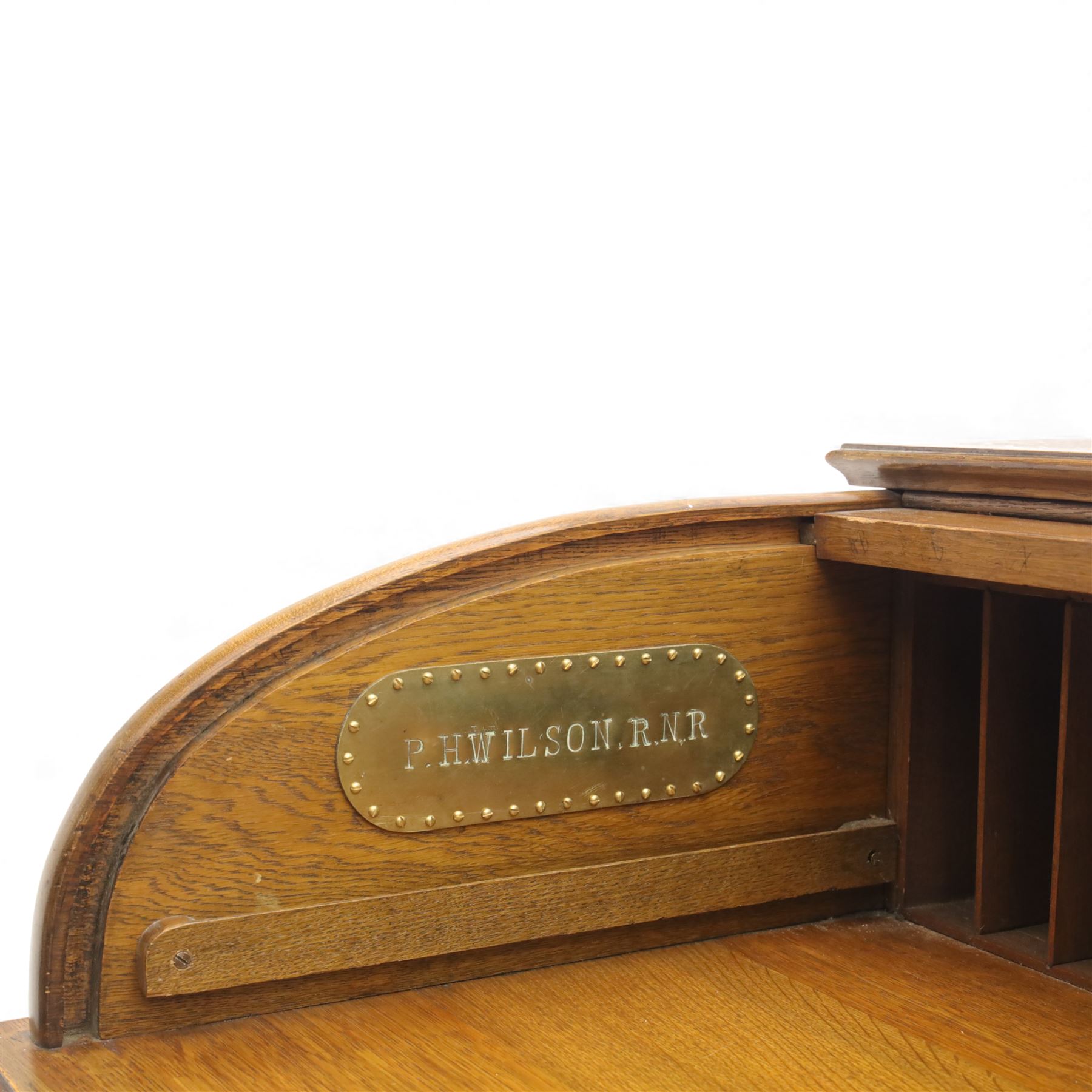 Edwardian oak roll-top desk, the tambour enclosing a fitted interior of pigeonholes and dividers, over a central kneehole flanked by twin banks of drawers with brass handles, on plinth bases