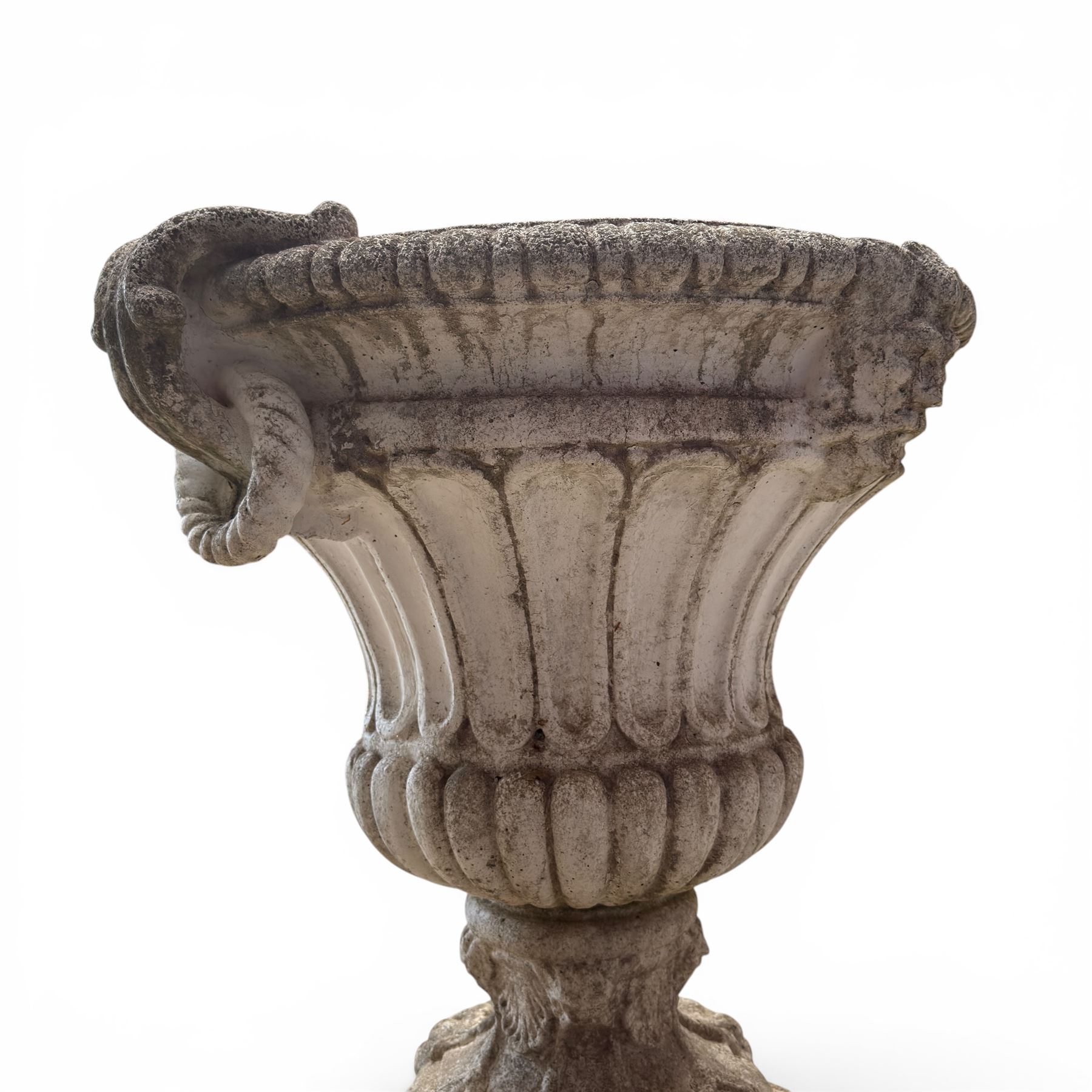 Pair of Neoclassical design cast stone garden urns, each of campana form with fluted body and gadrooned underbelly, decorated with faun/satyr opposing masks and ropetwist handles, with floral and mask design to the socles, raised on square bases, finished in weathered white patina