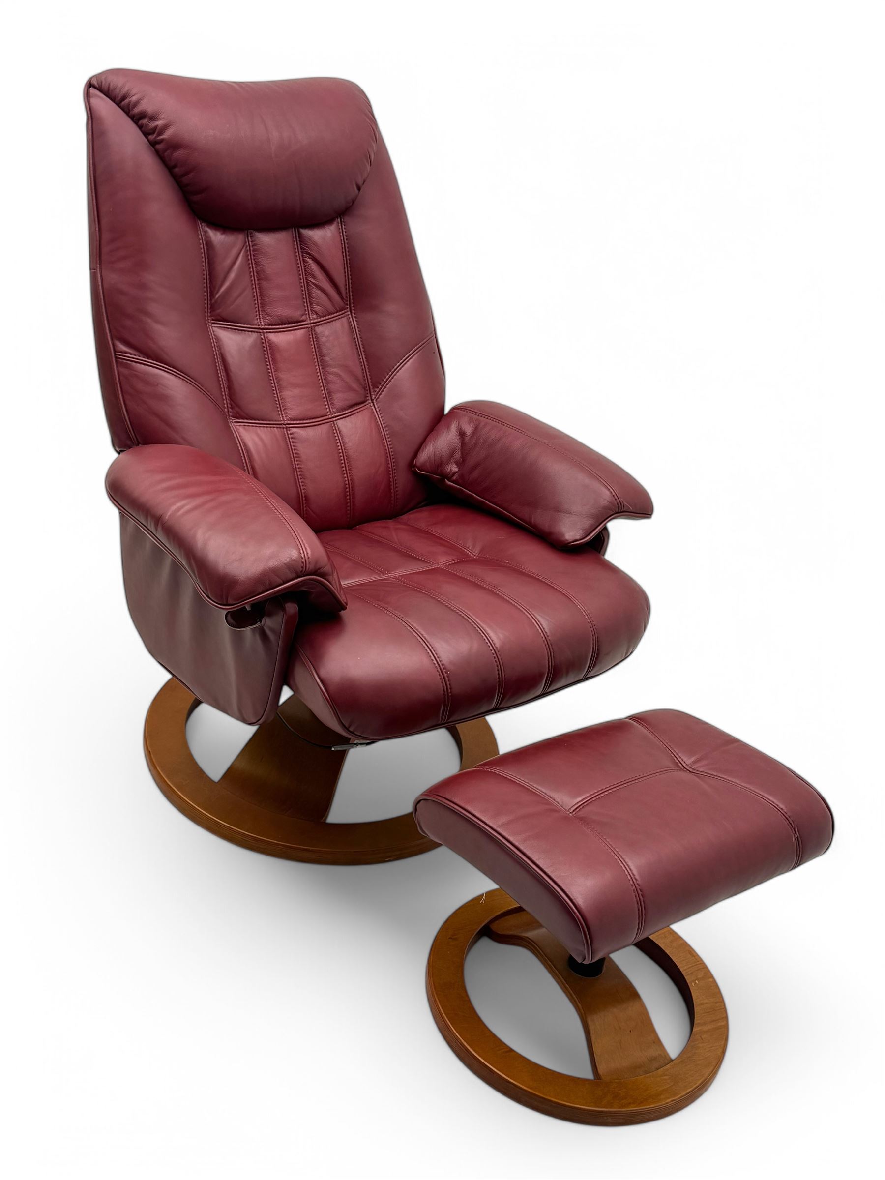 Contemporary burgundy leather reclining armchair and footstool, featuring segmented upholstered cushions and padded armrests, each piece mounted on a circular laminated wood base
