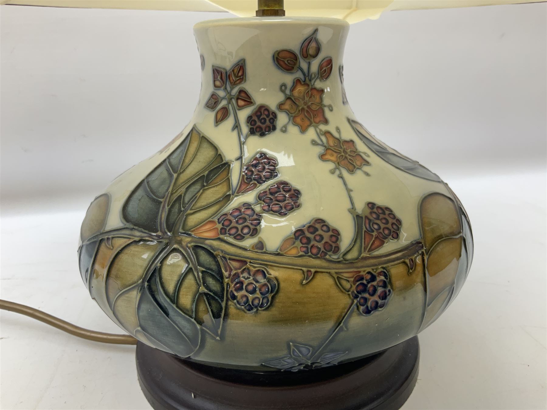 Moorcroft table lamp of squat baluster form, decorated in the Autumn Blackberry, with Moorcroft cream fabric shade with gold, green and red piping, overall H38cm