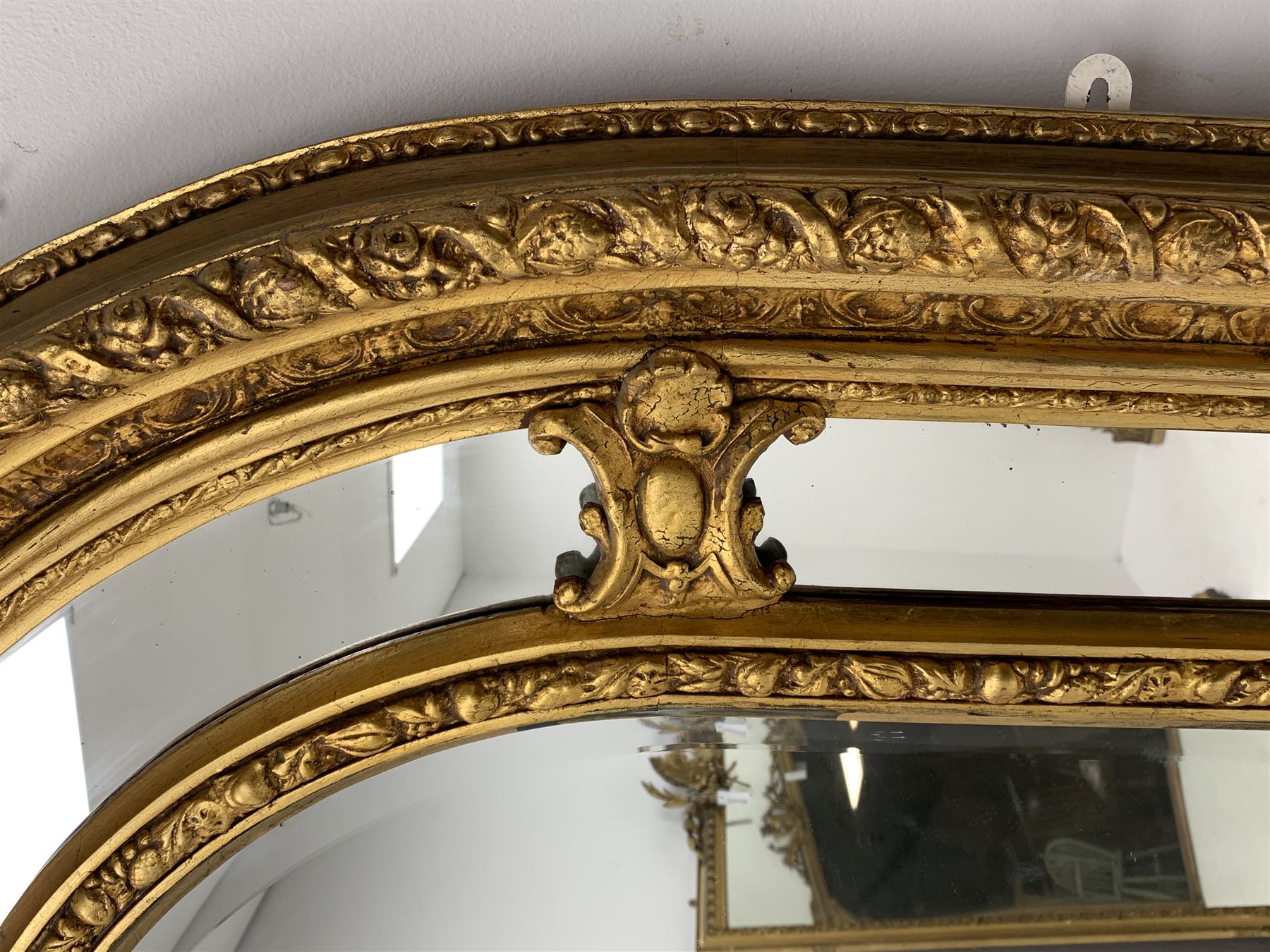Gilt Rococo style mirror, arched top with central cartouche and oak leaf moulded pediment, floral and fruit moulded surround with segmented glass panels, bevelled central pane, c-scroll shell and acanthus leaf brackets