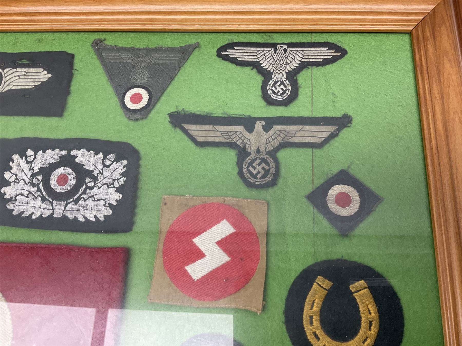 Framed display of thirty-four WWII German cloth badges including Luftwaffe pilot, Paratrooper, Afrikakorps cuff title, sleeve insignia for 'SS' Foreign Volunteers, various breast eagles including Luftwaffe, Army etc, RAD badges, Party Armband, rank and trade insignia, cap insignia etc; 40 x 50cm in modern pine frame