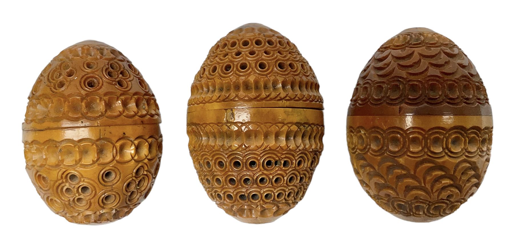 Three 19th century coquilla nut pomanders or flea catchers, each of egg shaped form with carved and pierced decoration and screw threaded join, largest example 6cm