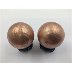 Pair of copper spheres, upon carved wooden bases, D5cm 