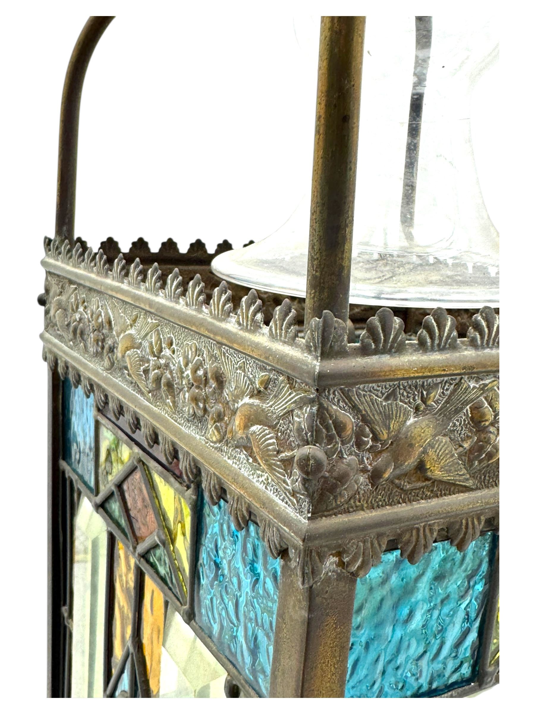20th century Gothic design stained glass and brass hall lantern, with ornately decorated frieze and apron, with geometric coloured glass panels and eight rectangular bevelled glass panels, with bell shade, wired for electricity 