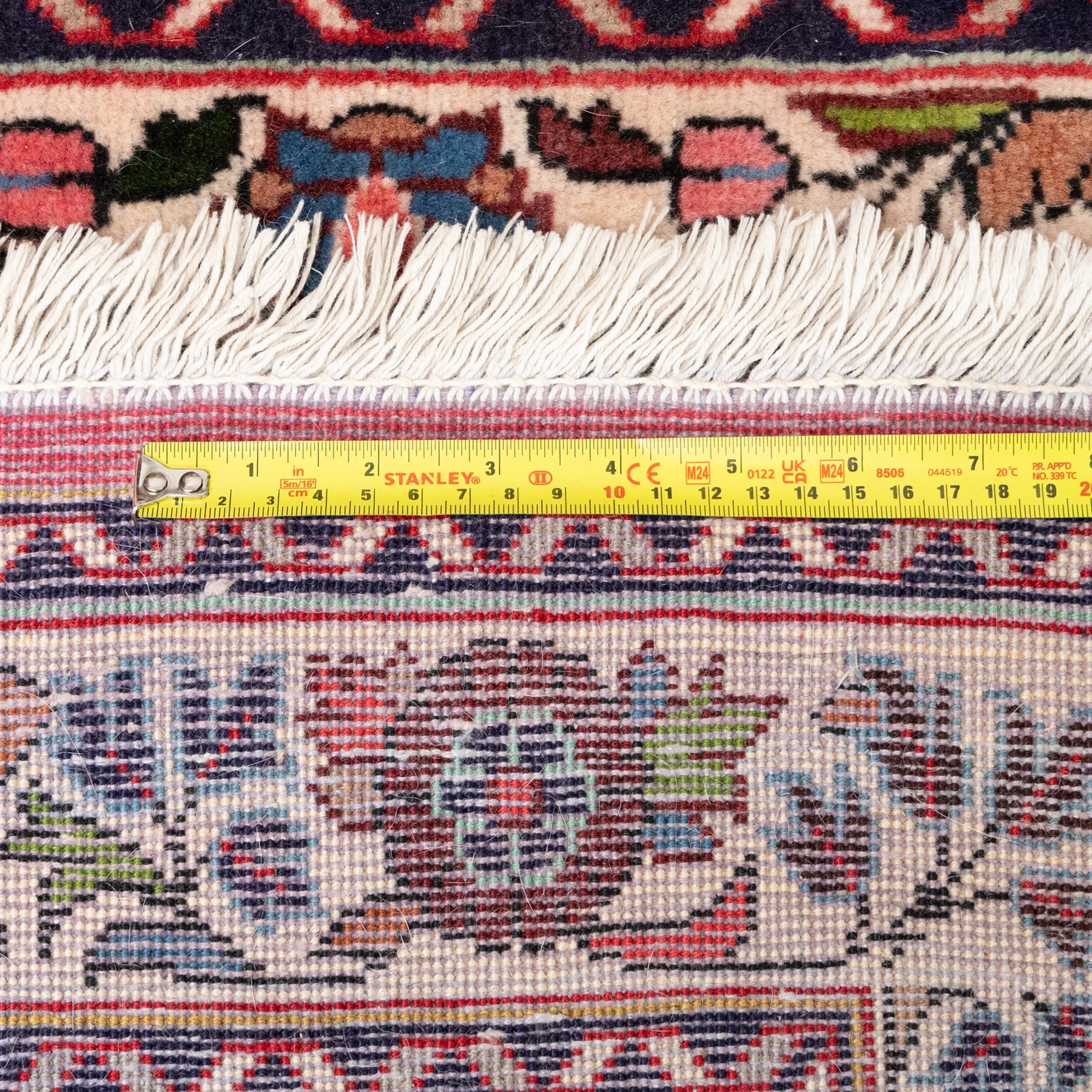 Persian rose ground runner rug, the field decorated with repeating polychrome floral sprays and scrolling palmettes, enclosed by an ivory floral border and narrow navy geometric guard stripes