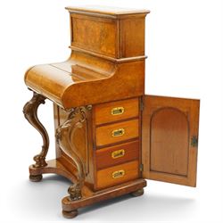 Victorian burr walnut piano-top Davenport, the raised rectangular superstructure with moulded cornice above a panelled fall-front enclosing drawers, the curved hinged writing slope opening to reveal a fitted interior above a sliding tooled leather writing surface, flanked by carved foliate scroll supports, the right side fitted with four drawers behind an arched panelled cupboard door with brass inset campaign-style handles, on a shaped plinth base and bun feet