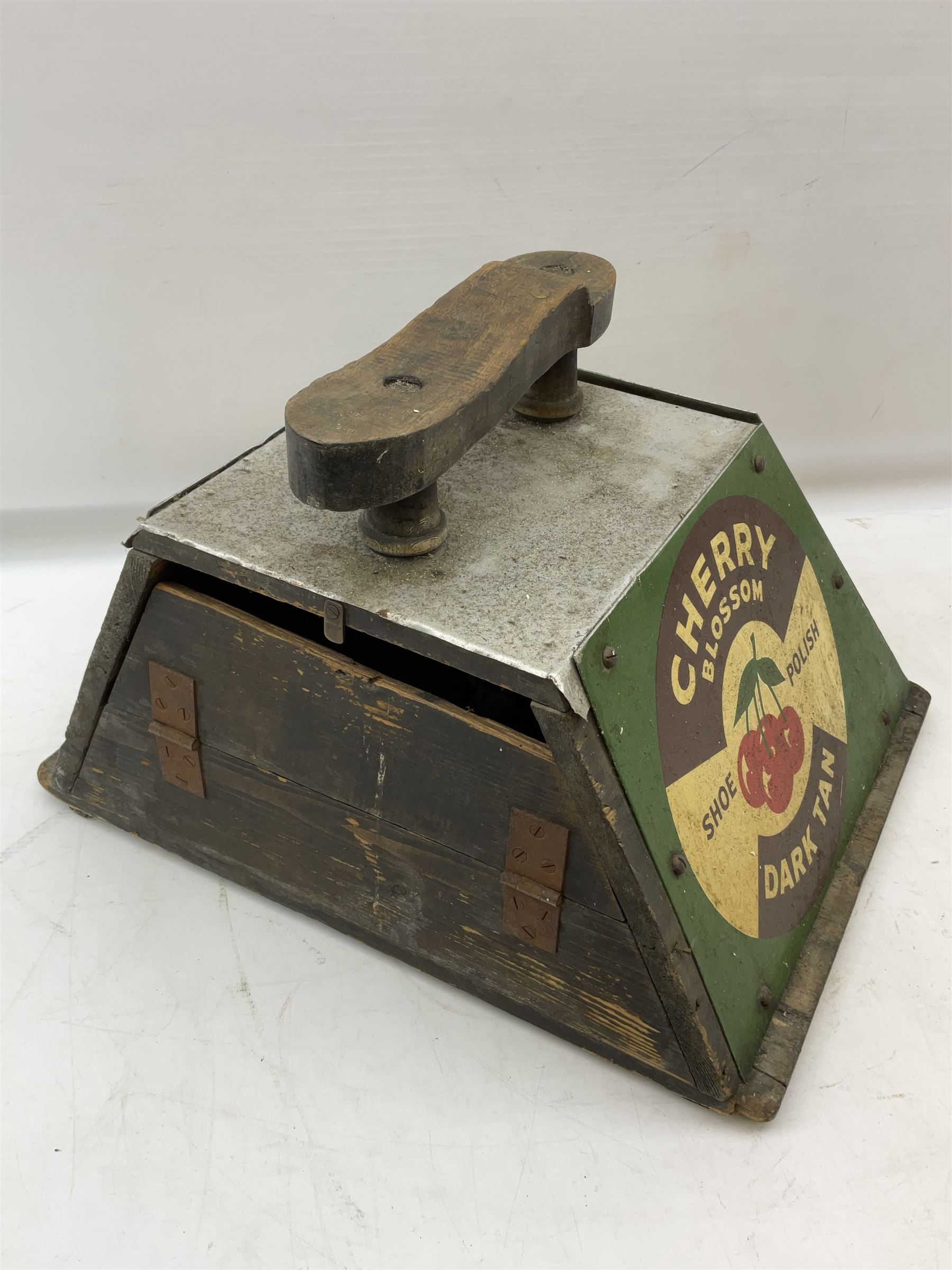 Cherry Blossom Shoe Polish shoe shine box, of sloping form, with three pictorial enamel panels advertising dark tan, black and light tan polishes, the reverse with a hinged compartment, the top mounted with a handle and foot rest in the form of a shoe sole, H29cm W42cm D33cm