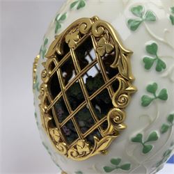 Franklin Mint The Emerald Isle Collector Egg, the egg decorated with embossed shamrocks upon a cream ground, with a gilded shamrock finial, accents and openwork door, opening to reveal a miniature landscape scene, upon three gilded feet set with green paste stones, with certificate of authenticity H23cm, 