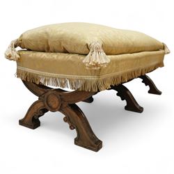 Late Victorian Gothic revival walnut long stool, rectangular padded seat upholstered in cream damask with tasselled corners and fringe border, raised on twin X-frame supports united by a turned stretcher, circa 1880