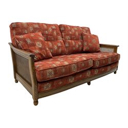 Ercol medium elm framed three seat bergere sofa, and pair of matching armchairs upholstered in red fabric