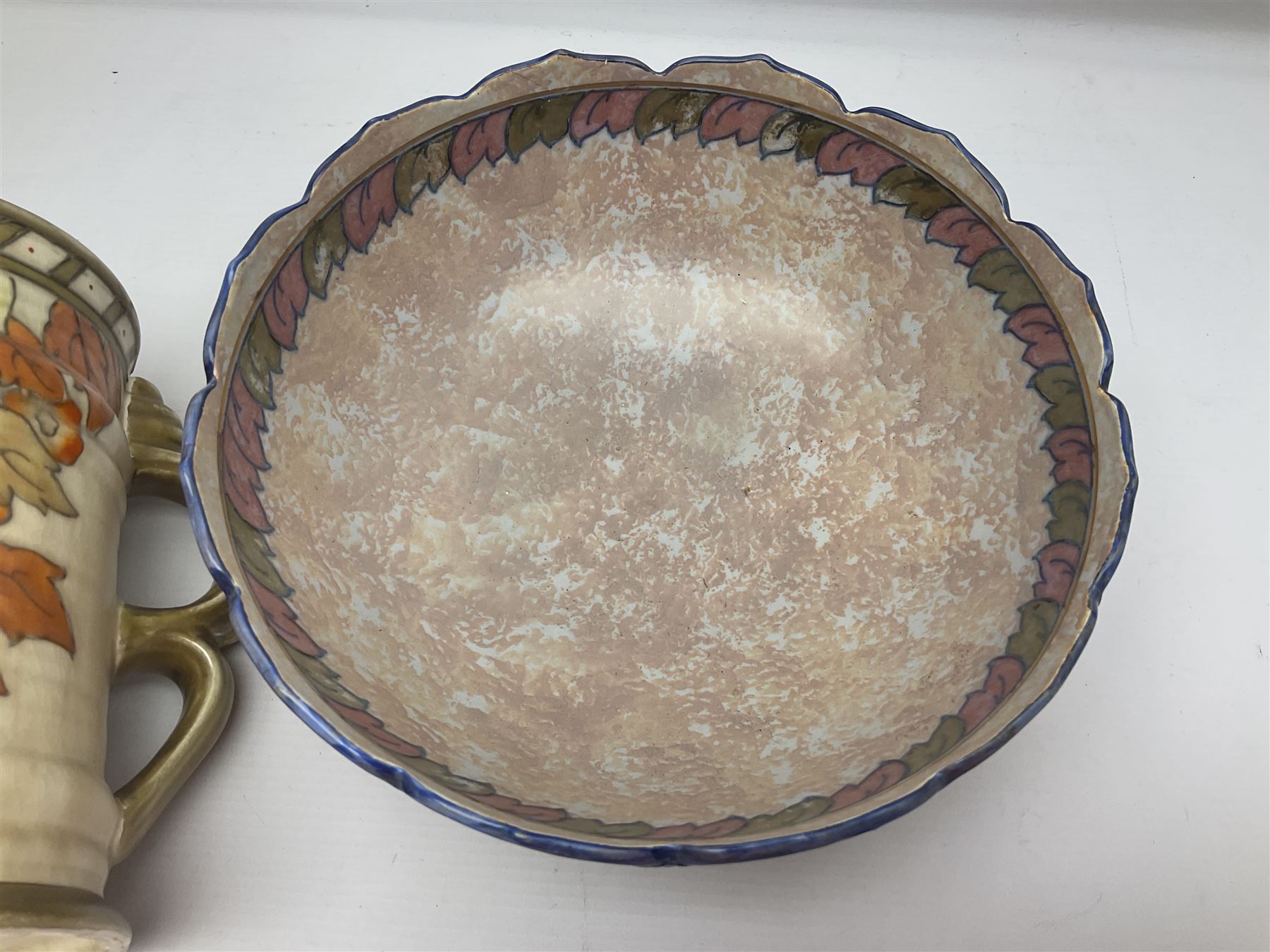 Charlotte Rhead for Crown Ducal ceramics, comprising coffin shaped vase depicting a woman in 1920s dress, a vase with handle, decorated with autumn leaves and a bowl, decorated with flowers and berries, with printed and signed marks beneath, coffin vase H24cm