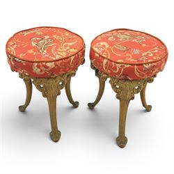 Britannia style cast iron pub table and pair of stools, moulded circular top raised on a gilt painted frame, featuring masks and acanthus detailing united by an under tier, the stools with red floral design (Stools diameter 34cm, height 47cm) 