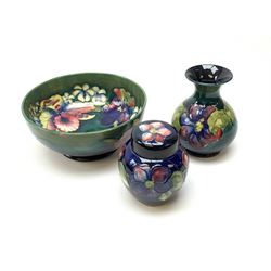 Three pieces of Moorcroft pottery, comprising bowl decorated in the Orchid pattern upon a green glazed ground, D19cm, and vase and ginger jar decorated in the Anemone pattern, each with impressed marks beneath, one with painted mark, and another with paper label remnants. (3).