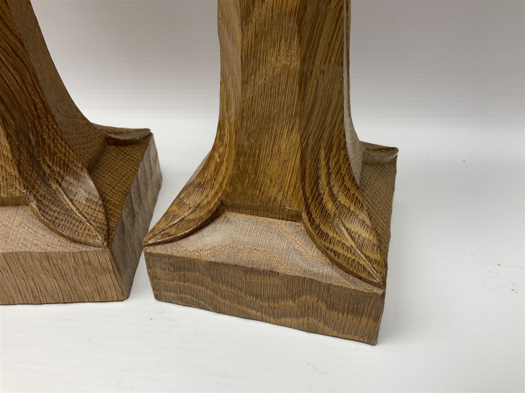 Mouseman - pair of tooled oak candlesticks, wrought iron sconce with drip tray over tapered octagonal column carved with mouse signature, terminating to stylised leaf carved square base, by the workshop of Robert Thompson, Kilburn
