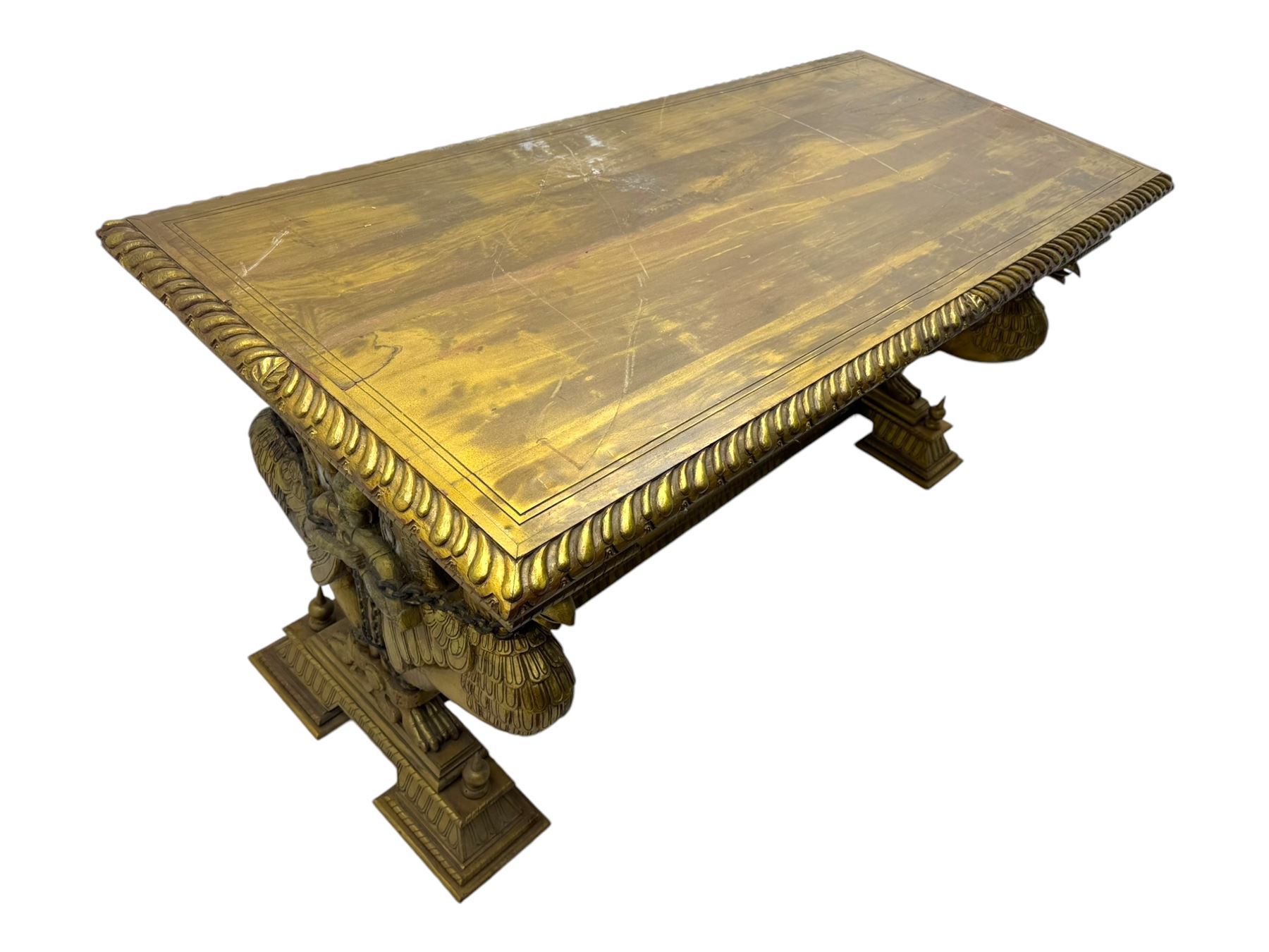 19th century Renaissance Revival carved and giltwood centre table, the rectangular top with gadrooned edge and carved frieze of repeating arched motifs with stylised scrolls, supported by a pair of carved winged griffin supports restrained by a central chained figure, on stepped rectangular bases united by carved stretcher