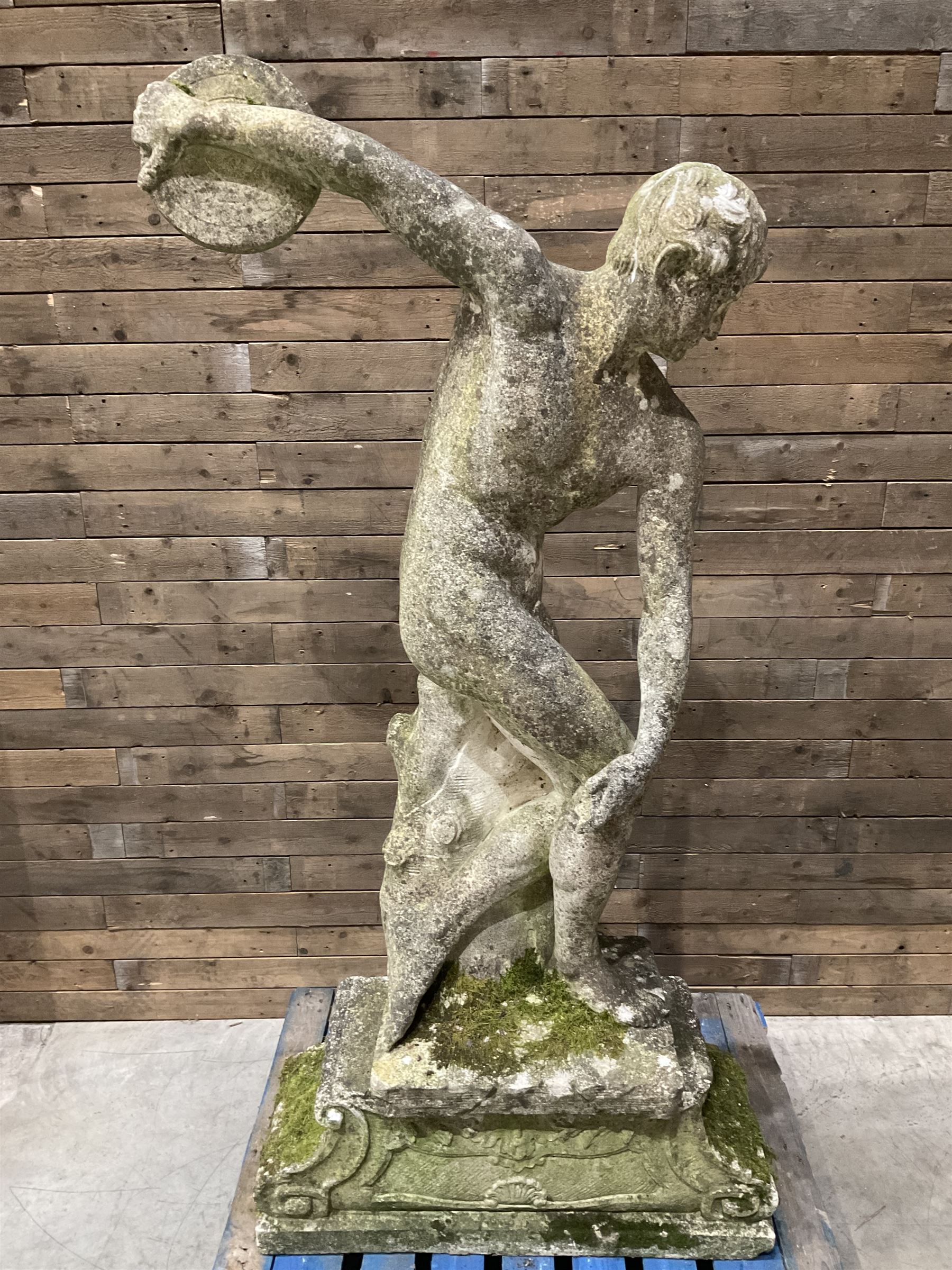 Life-size weathered cast stone Greek Discus Athlete, seated on rectangular slab raised on associated architectural plinth