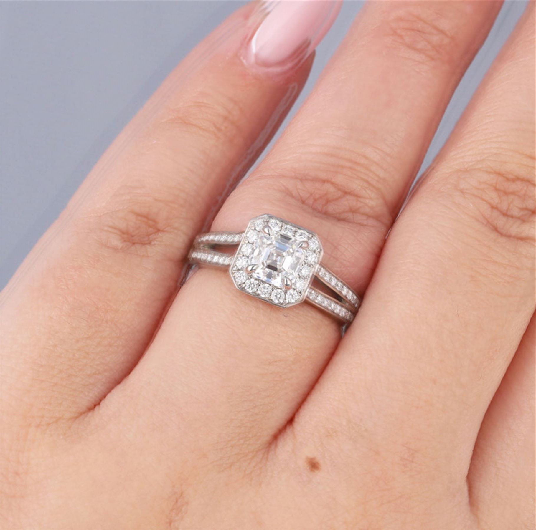 Platinum diamond cluster ring, the principal asscher cut diamond of 1.01 carat, with HRD report, colour F, clarity VS1, with round brilliant cut diamond surround and diamond set shoulders, hallmarked, total diamond weight 1.34 carat