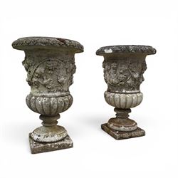 Pair of quality antique weathered three-piece composite stone garden urns, the flared rim moulded with repeating acanthus leaves, over a deep-relief campana body decorated with fruiting grapevines and ivy leaves, the gadrooned underbelly over a turned socle and square base