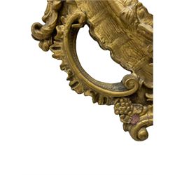 19th century gilt wood and gesso wall mirror, the cartouche pediment over oval shell scalloped frame with foliate moulded inner slip, the frame mounted by trailing and scrolled leafage with C-scrolls, the lower shaped section decorated with foliage and fruit, plain mirror plate 