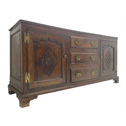 George III oak dresser base, fitted with three graduating central drawers, flanked by two arched fielded panel doors, the facias carved with a lozenge with central rosette, lower moulded rail over bracket feet